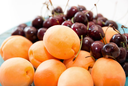 Fresh apricots and cherry on a plateの写真素材