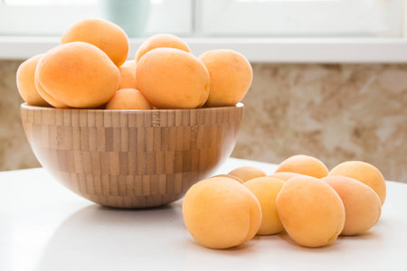 Apricot. Group of fresh fruits in a wooden bowl on a white tableの写真素材