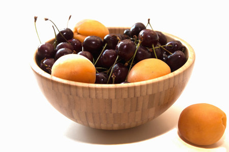 Fresh apricots and cherry in a wooden bowlの写真素材