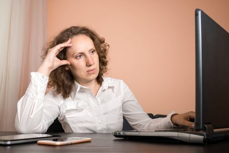 tired woman with a headache using a laptopの写真素材