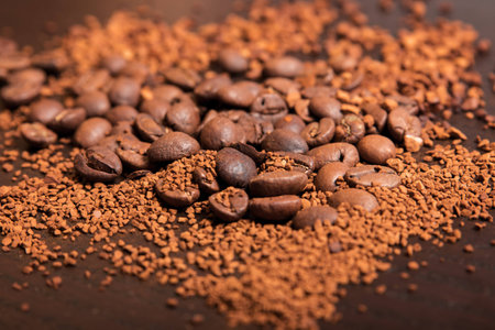 Coffee beans and ground coffee on a dark brown tableの写真素材