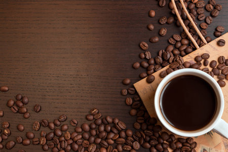 Cup of coffee and coffee beans on dark brown tableの写真素材