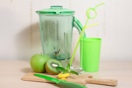 Cooking smoothie of kiwi, apple, lemon and mint. Blender, knife, glasses, straw and wooden boardの写真素材