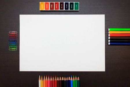 Color pencils, paints, clips, markers and white sheet on dark backgroundの写真素材