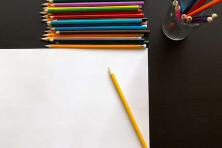 Colored pencils and sheet of paper on dark backgroundの写真素材