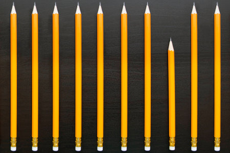 Row of identical pencils with one different on dark backgroundの写真素材