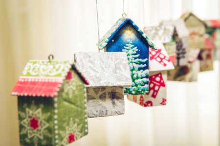 Fir tree decoration: handmade houses with Christmas ornaments hanging on a stringの写真素材