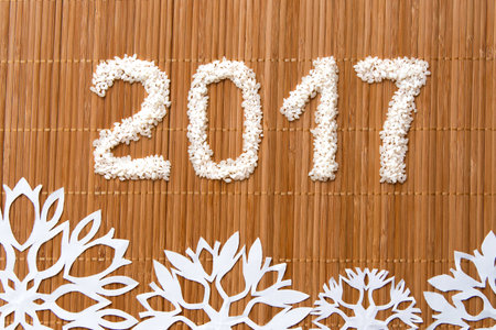 Christmas and New Year composition of white rice and snowflakes on matの写真素材