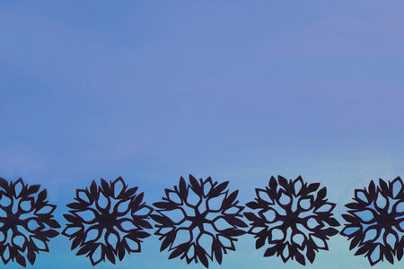 Blue New Year and Christmas background with black snowflakes for your textの写真素材