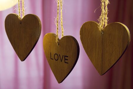 Valentines day wooden hearts with the word love on a pink backgroundの写真素材