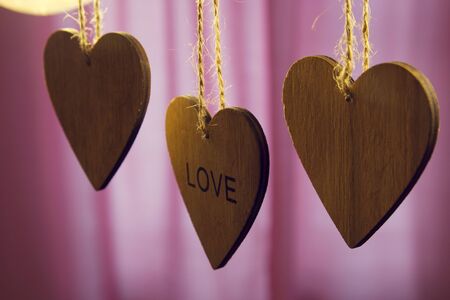 Valentines day wooden hearts with the word love on a pink backgroundの写真素材