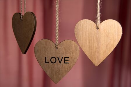 Valentines day wooden hearts with the word love on a pink backgroundの写真素材