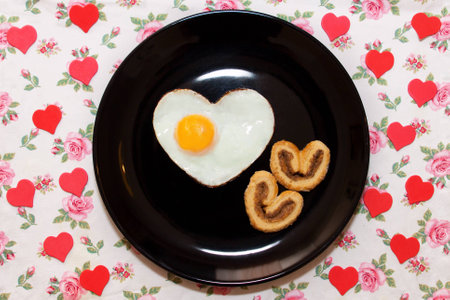 Composition of biscuits and egg in a heart shape on black plate. Valentine's Dayの写真素材