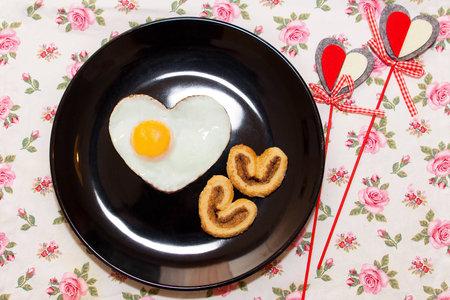Composition of biscuits and egg in a heart shape on black plate. Valentine's Dayの写真素材