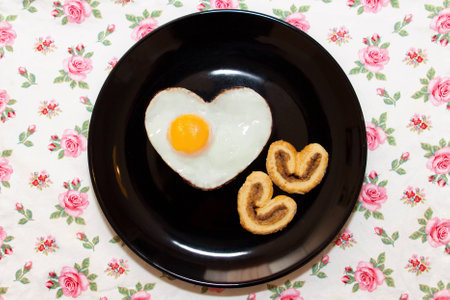 Composition of biscuits and egg in a heart shape on black plate. Valentine's Dayの写真素材