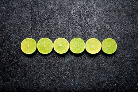 Top view of row of cut limes on dark background の写真素材