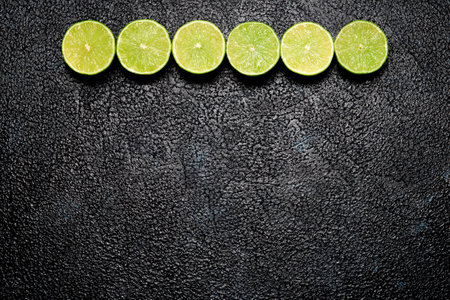 Row of halves of limes on dark background with copyspace for your textの写真素材