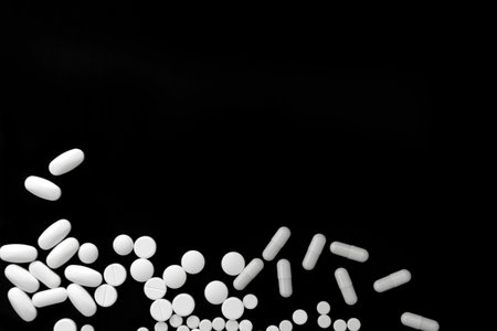 Bunch of various white pills on black background with space for textの写真素材