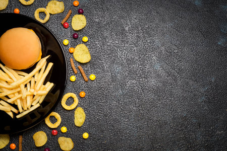 Fast food: top view of burger, french fries, chips, rings and candies with space for text. Unhealthy eating concept の写真素材