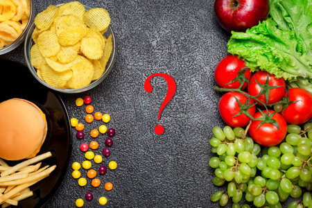 Healthy nutrition concept. Fruits and vegetables vs unhealthy fast food and sweetsの写真素材