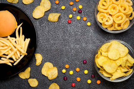 Fast food: top view of burger, french fries, chips, rings and candies with space for text. Unhealthy eating concept の写真素材