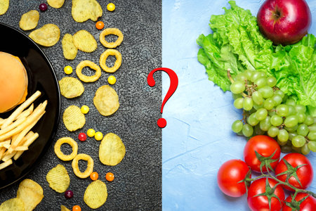 Healthy nutrition concept. Fruits and vegetables on light table vs unhealthy fast food and sweets on dark tableの写真素材