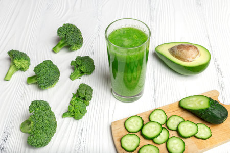 Green smoothie from broccoli, avocado, kiwi and cucumber on white wooden tableの写真素材