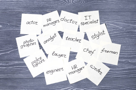 Stickers with different professions on gray wooden background. Profession choosing conceptの写真素材