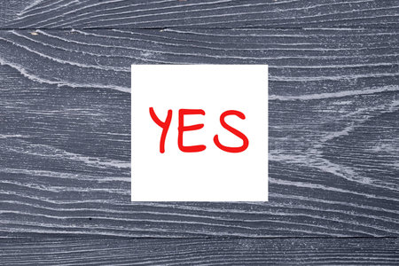 Red word "Yes" on white sticker on gray wooden backgroundの写真素材