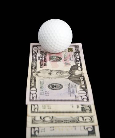 a ball for golf lies on notes on a black backgroundの写真素材
