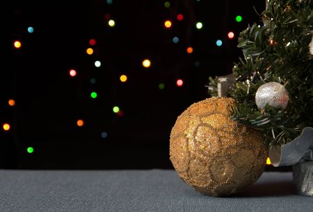 golden ball under a decorated Christmas tree in the background colour of the lightsの写真素材