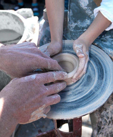 hand of the potter and the child in the creation of new products from clayの写真素材