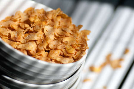 corn flakes poured from a plate stacked on the white table closeup