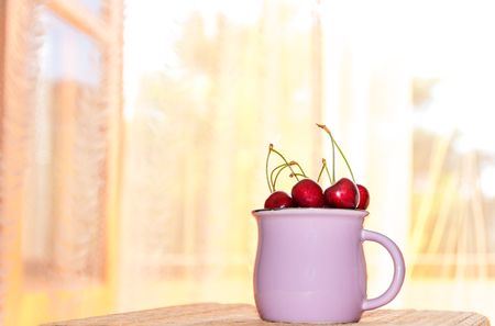 Cup with a cherry on a morning window backgroundの写真素材