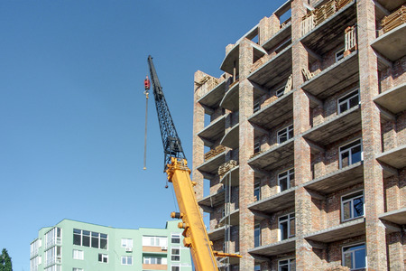 a construction crane near two residential buildings of houses built and being built