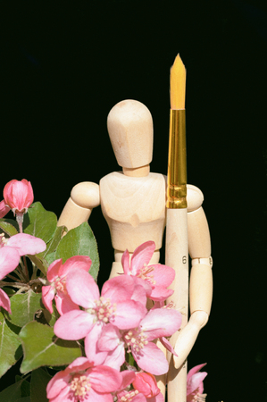 Wooden model with a brush among the red flowers of an apple treeの写真素材