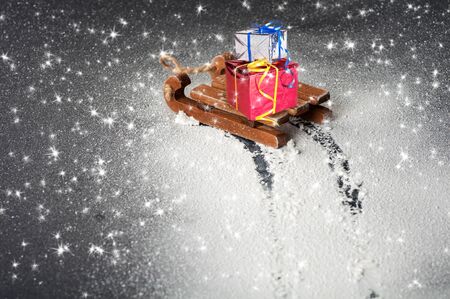gifts on a wooden sleigh, trace of a sleigh on white snow on a black backgroundの写真素材