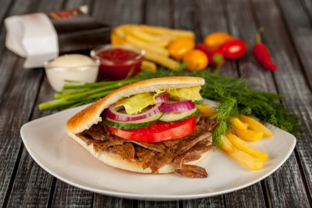 Pita with grilled meat and vegetables on wood backgroundの写真素材