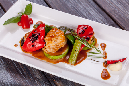 Vegetables and chicken grilled with sauce on a plateの写真素材