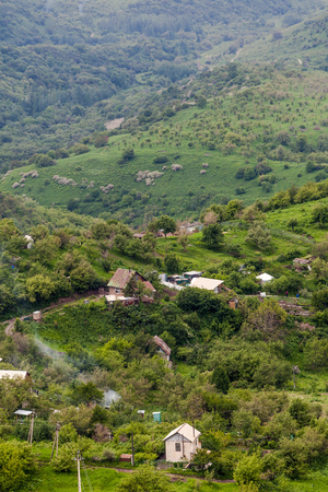 The green foot of the mountain with small houses, the countryside. Vertical formatの写真素材