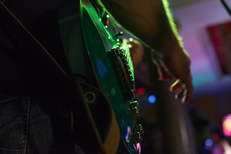 Musician plays bass guitar on stage in neon light close upの写真素材