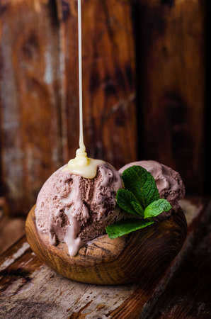 Chocolate ice cream with condensed milk on the wooden background