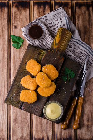 Chicken Nuggets on wooden cutting board with ketchup and sauce, on wooden background. Selective focus. Top viewの写真素材