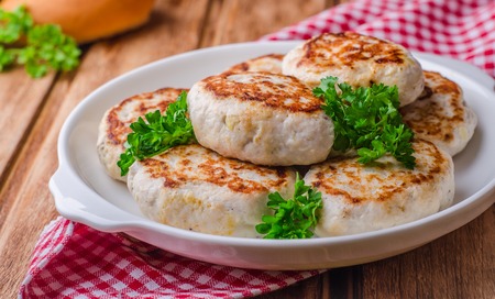 Cutlets on bowl and wooden background