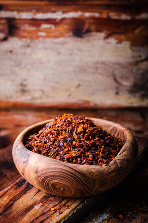 Pul biber - crushed red chili pepper in vintage bowl on wooden background. Selective focus. Toned image. Turkish cuisineの写真素材
