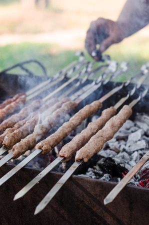 Man cooking marinated shashlik or shish kebab, chiken meat grilling on metal skewer, close up. Ramadan foodの写真素材