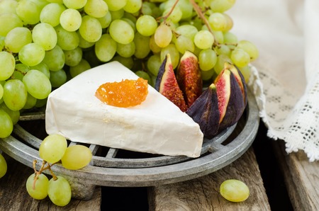 Grape, cheese and figs with on wooden vintage table background.の写真素材