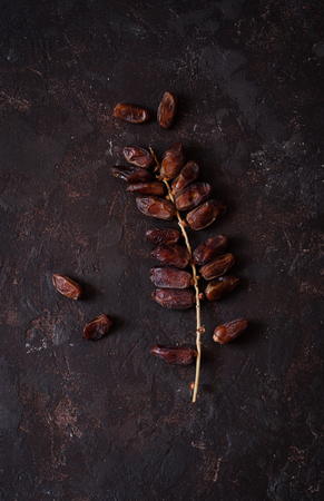 bunch of date fruits with palm on dark stone backgroundの写真素材
