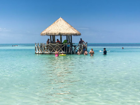COCOCAY, BAHAMAS - APR 2019. Group of tourists enjoying at a beach bar on a paradise island.のeditorial素材