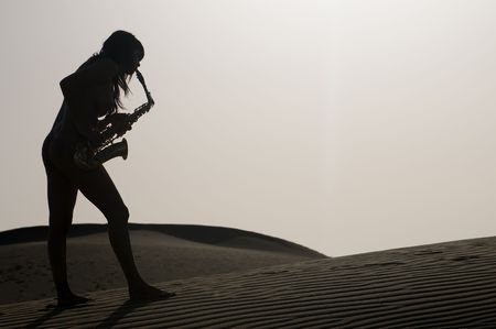 silhouette of a woman playing saxophone under the skyの写真素材